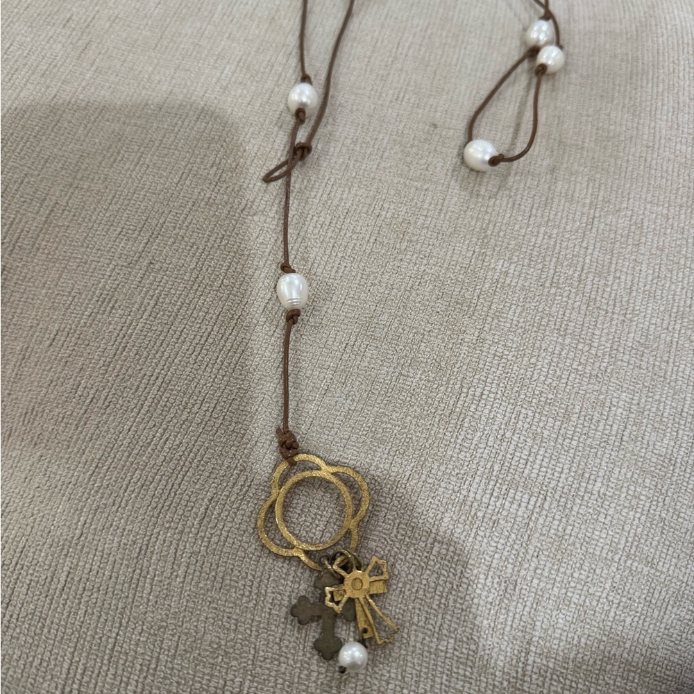 Necklace with white beads and gold cross pendant.